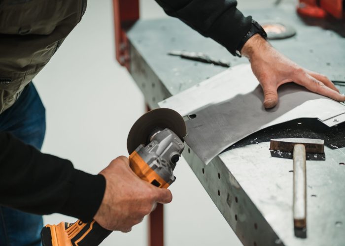 Technician worker working with a metallic part in the garage Using equipment